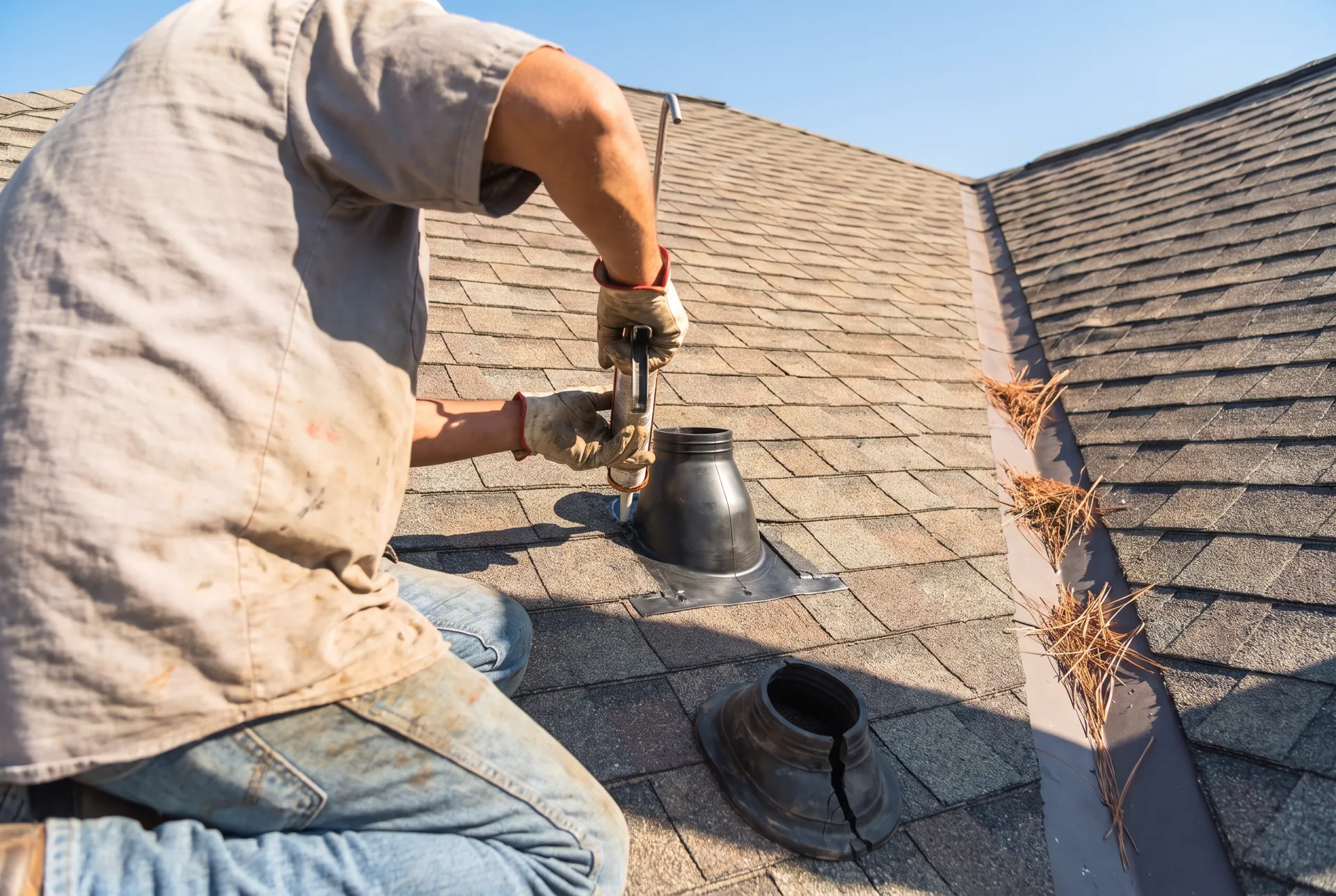 Roofer replacing a cracked pipe boot and resealing flashing on an asphalt shingle roof in the Texas sun
